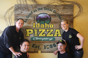 Idaho Pizza Company Employees surround a printed Idaho Pizza logo sign. 